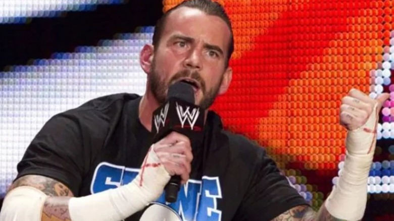 CM Punk sits cross-legged on the stage and delivers his infamous "pipe bomb" promo during an episode of "WWE Raw."