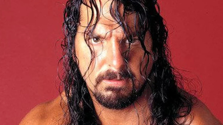 Chris Kanyon poses for a photo backstage, staring menacingly into the camera with his hair in his face.