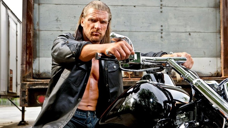 Triple H poses for a photoshoot while sitting on a motorcycle.