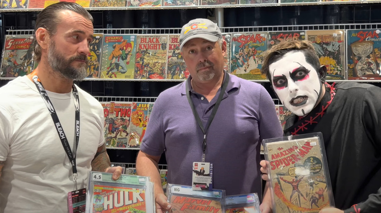 CM Punk glaring at Danhausen with a comic book seller between them