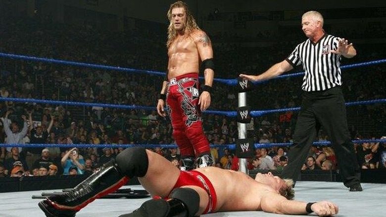 Edge (Adam Copeland) and Chris Jericho compete in a WWE World Heavyweight Championship match. Edge looks down at Jericho, who is lying on the mat