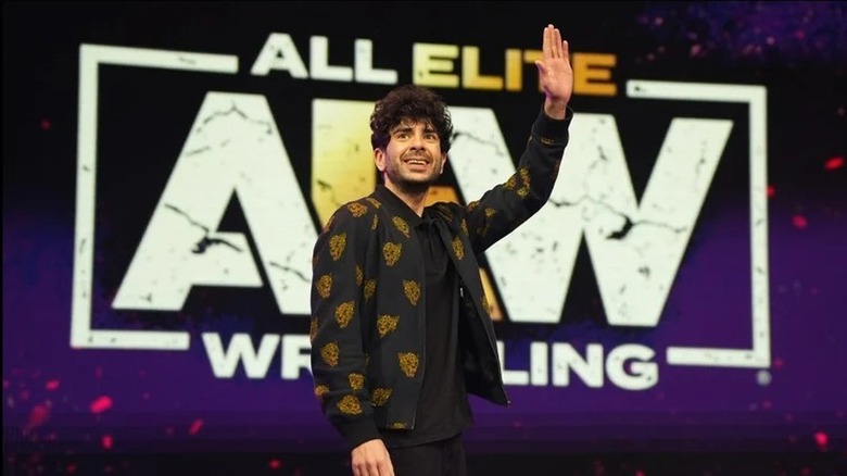 AEW President and CEO, Tony Khan, waves out towards the crowd during a live event.
