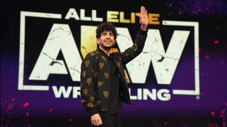 AEW President and CEO, Tony Khan, waves out towards the crowd during a live event.