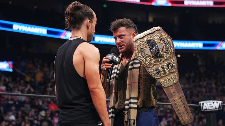 MJF holding up the AEW World Championship in front of Adam Cole