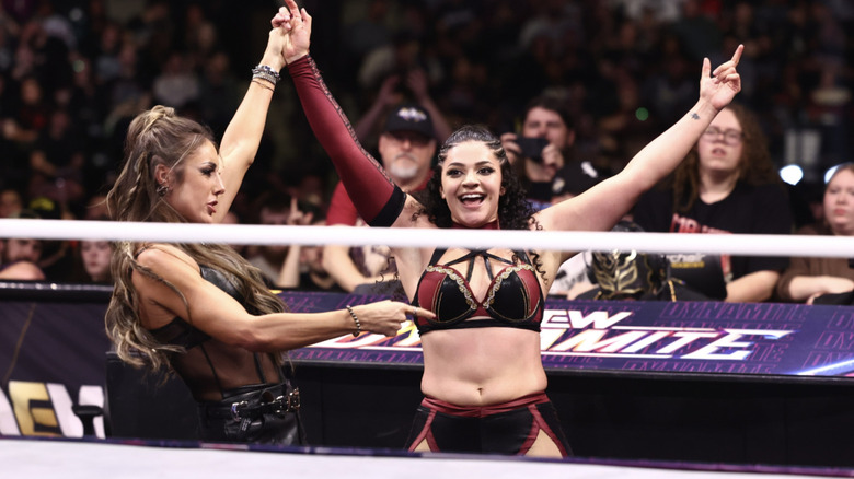 Baker raising Persephone's arm on the outside of the ring