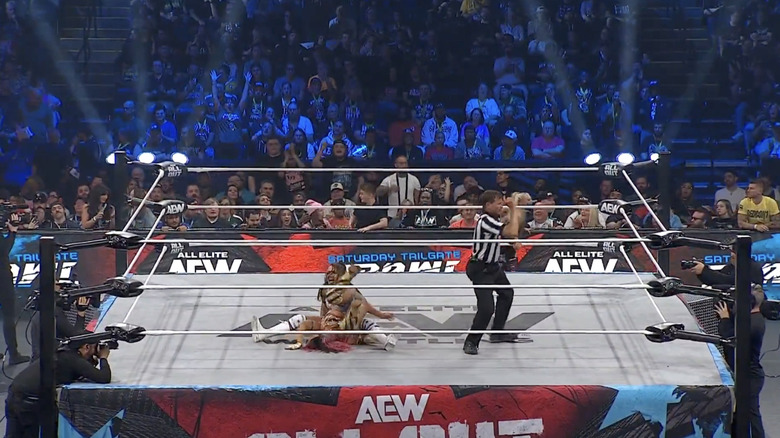 Blue pinning Shirakawa as Hart stands on the outside