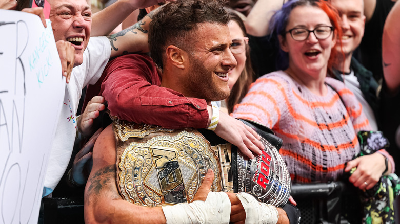MJF smiles while holding both of his title belts