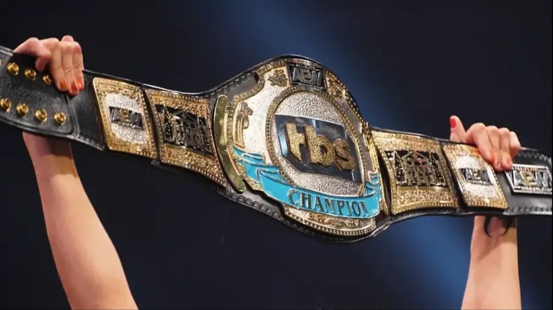 A photo showing the TBS Championship being held up by AEW referee Aubrey Edwards