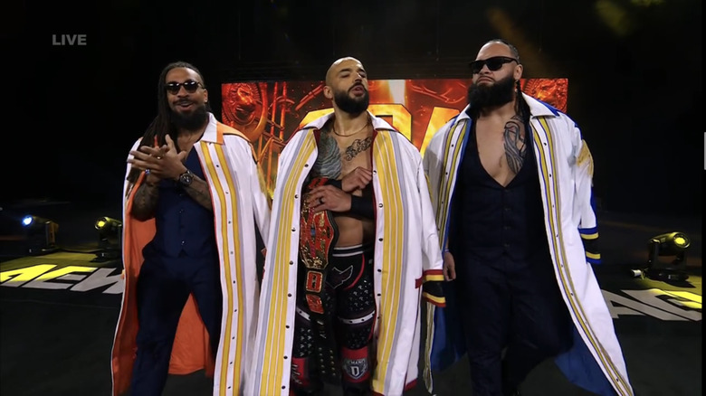 Ricochet walks alongside Toa Liona and Bishop Kaun as he makes his entrance with the AEW National Championship.