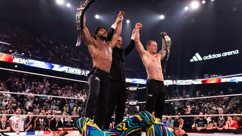 Kevin Knight and Kyle Fletcher, alongside Don Callis, hold up the Young Bucks' AEW World Tag Team Championships, as the champions lay in the ring, to end the October 10, 2026 edition of 