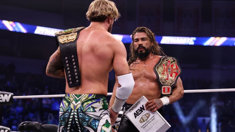 Andrade El Idolo holding his contract and looking at the AEW Men's World title