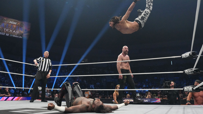 Nicholas Jackson flies from the top rope to hit Swerve Strickland below, as Jon Moxley stands on the ring apron, during a match on "AEW Dynamite."