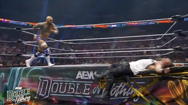 Ricochet about to land a moonsault on Briscoe off the apron and onto the stretcher