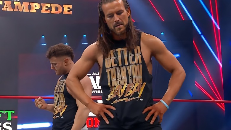MJF looks down at his diamond ring behind Adam Cole's back