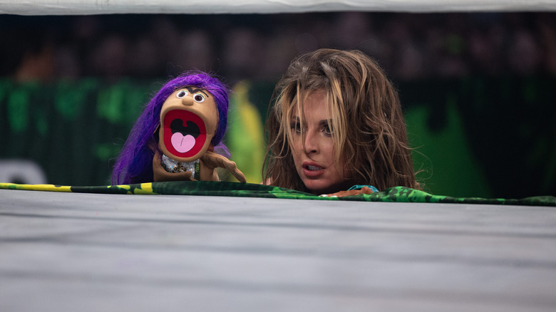 Harley Cameron and the puppet Mercedes Mone peak over the ring apron at AEW Grand Slam Australia.