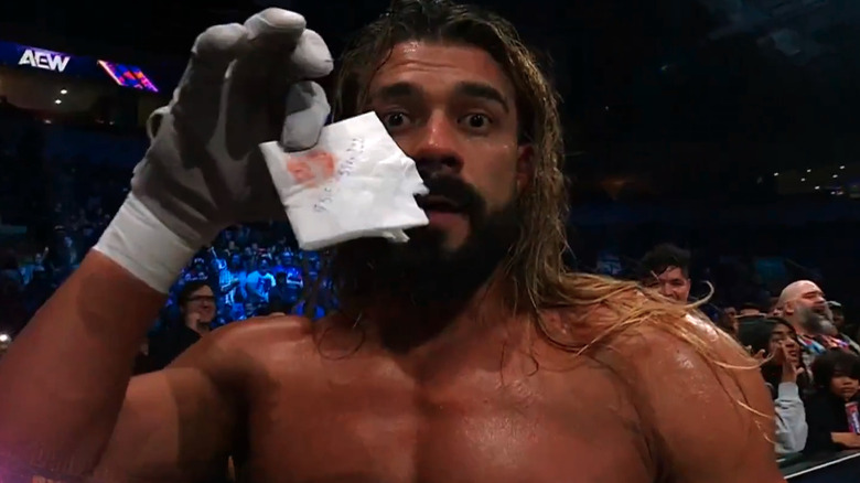 Andrade holds up a piece of paper with lipstick and a phone number on