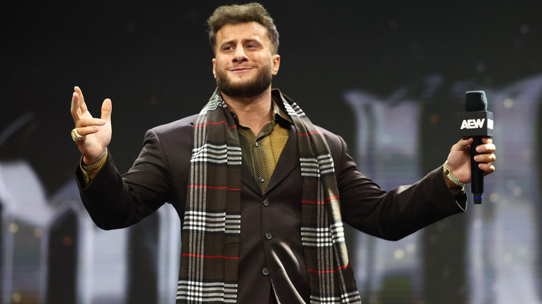 MJF stands on the stage and poses for the crowd while holding a microphone on an episode of "AEW Dynamite."