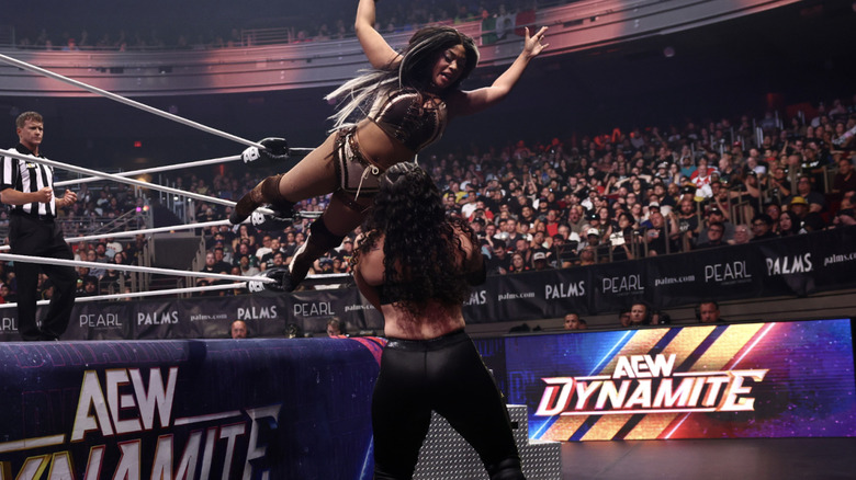 World flying off the ring apron to land a crossbody on Persephone