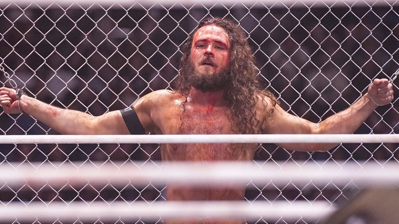 Jack Perry, handcuffed to a steel cage.