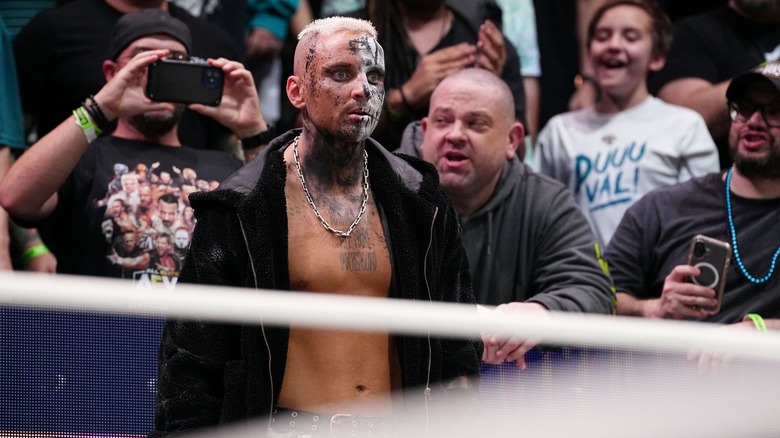 Darby Allin gives a thousand-yard stare as fans film and rile him on in the background.