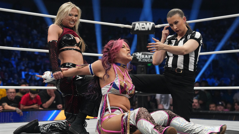 Julia Hart puts Mina Shirakawa in a submission hold in the middle of the ring as referee Aubrey Edwards checks on her during an episode of "AEW Dynamite."