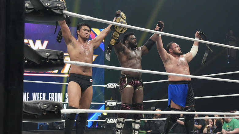 The Opps standing tall in the ring holding up their title belts