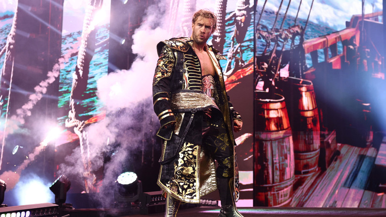 AEW World Champion Will Ospreay poses on stage, his Assassin's Creed: Black Flag-themed titantron playing behind him, ahead of his match at AEW All Out 2026.