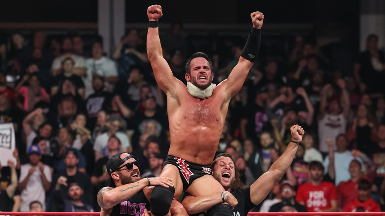 Mike Bennett and Matt Taven holding up Roderick Strong