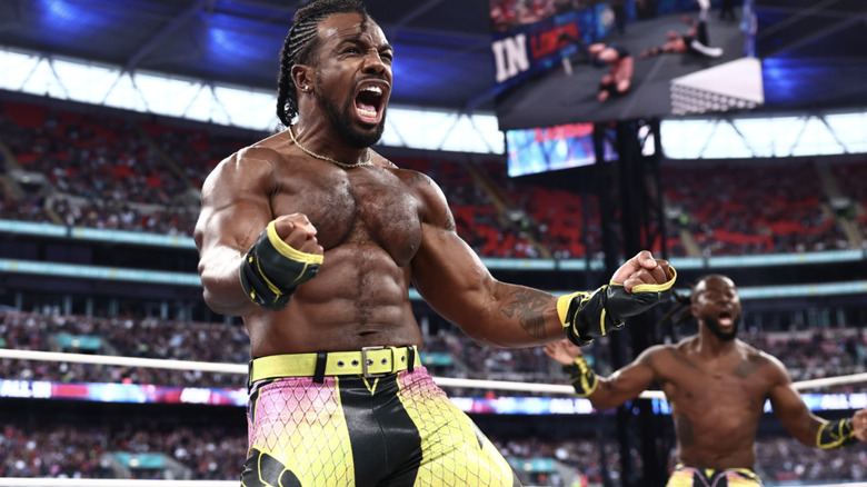 Creed celebrating in the ring at All In as Kofi stands behind him