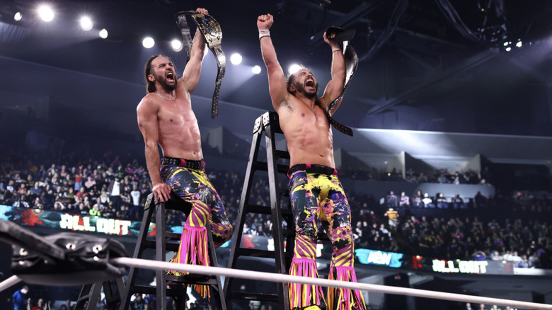 The Young Bucks holding up the AEW World Tag Team Championship belt on top of a ladder