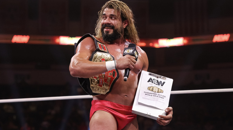 Andrade with his National Championship belt and future AEW World Championship match contract