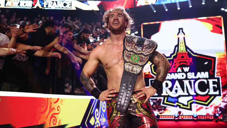 AEW World Champion Will Ospreay poses with the title on his shoulder, while standing on the stage, after his victory over Kazuchika Okada at 