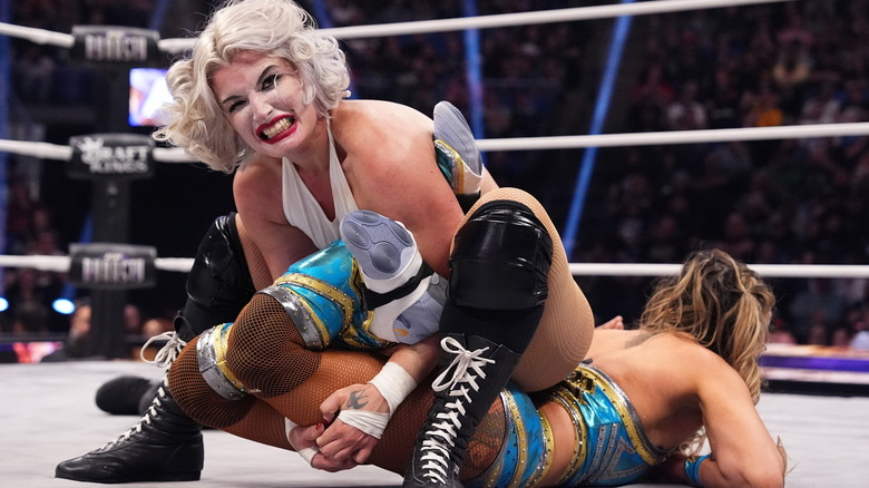 Toni Storm bears her teeth as she cinches in a Cloverleaf submission onto Thunder Rosa