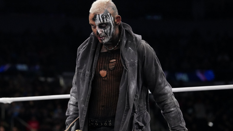 Darby Allin stands, armed with his skateboard, in the ring as he stares down Don Callis and Andrade El Idolo.