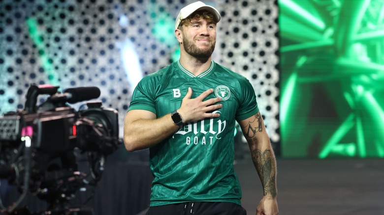 Will Ospreay smiles as he puts a hand on his heart during an entrance.