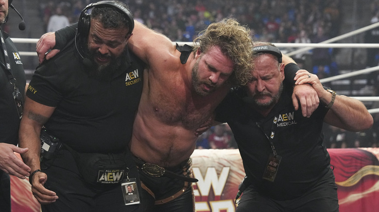 "Hangman" Adam Page is helped to the back by two AEW officials following a post-match beatdown by Samoa Joe at WrestleDream.
