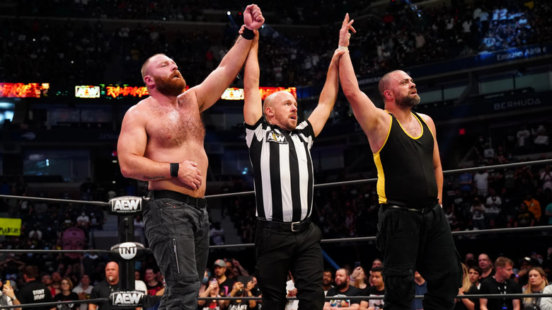 Jon Moxley and Eddie Kingston having their arms raised by Bryce Remsburg