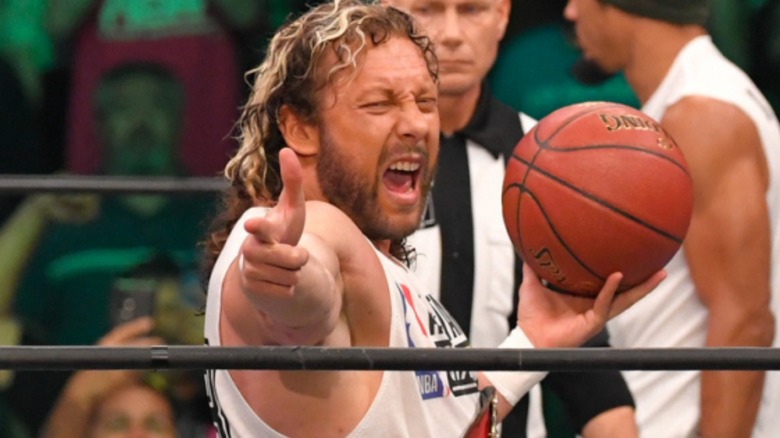 Kenny Omega displaying finger guns and a basketball