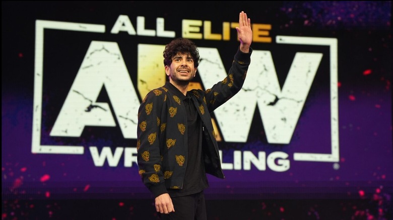 AEW President and CEO, Tony Khan, waves out towards the crowd during a live event.