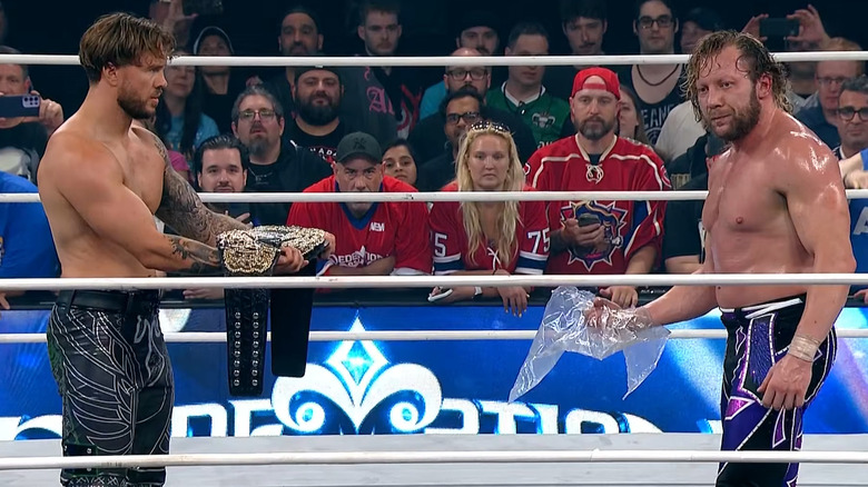 Will Ospreay giving Kenny Omega the AEW World title while Omega holds plastic bag