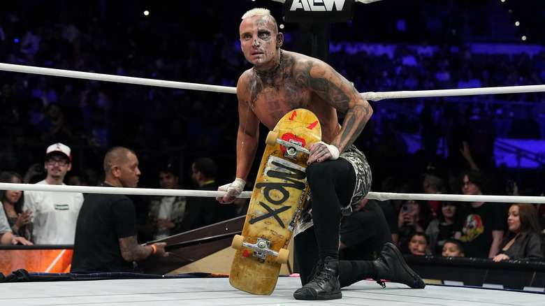 Darby Allin arms himself with his skateboard in the middle of the ring during a match on AEW television.