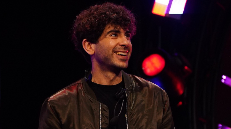 Tony Khan, taking a break from trolling on Twitter, smiles, knowing another Battle of the Belts is coming
