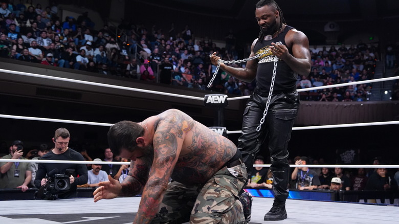Swerve Strickland stands over Brody King, a chain in his hands, during a beat-down segment on "AEW Dynamite."