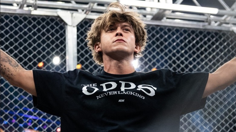 Hook proudly holds his arms up in the air after helping Samoa Joe win the AEW World Championship for a second time