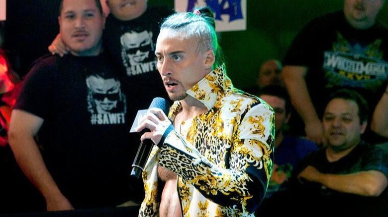 Former WWE star Enzo Amore talks on the microphone as he approaches an "WWE NXT" ring