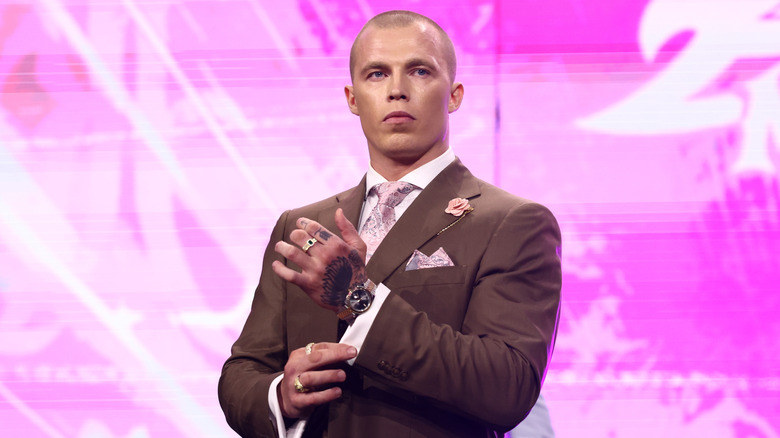 Kyle Fletcher stands on the stage, looking to the ring at rival Konosuke Takeshita, during an episode of 