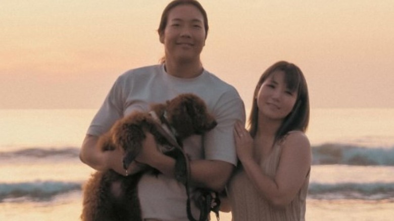 Konosuke Takeshita and Yuka Sakazaki pose on a beach, Takeshita holding their dogs, in an Instagram announcement of their marriage.