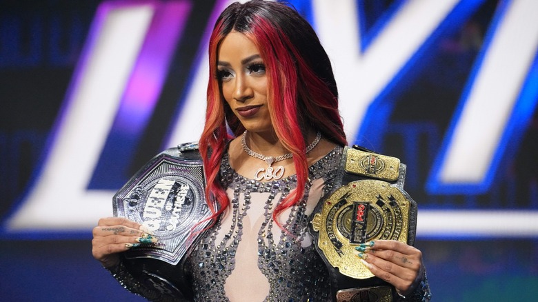 Mercedes Mone posing with her titles watching the Kris Statlander and Jamie Hayter match on 