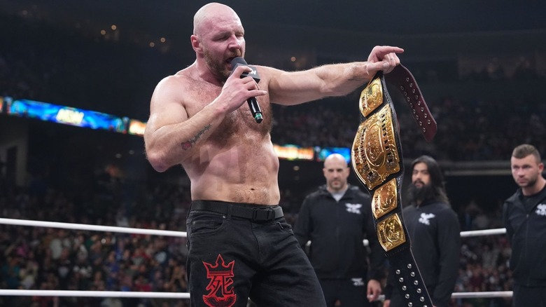 Jon Moxley points while holding his new title and speaking into a microphone at AEW Worlds End