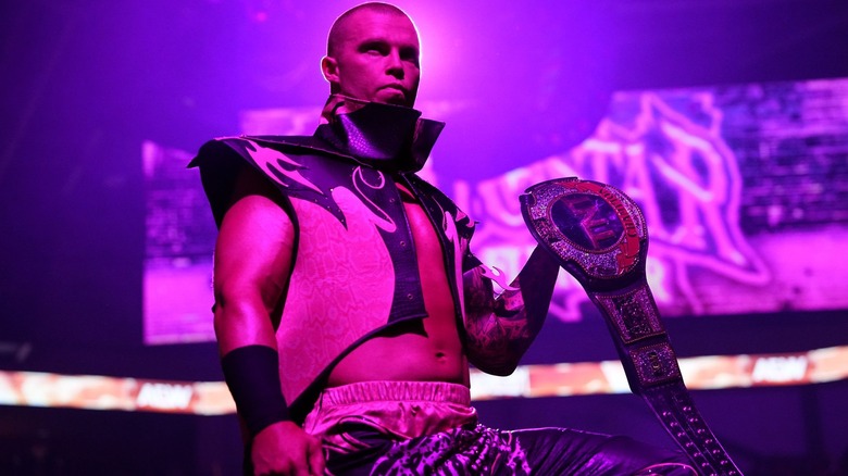 Kyle Fletcher is bathed in pink as he holds his TNT title.